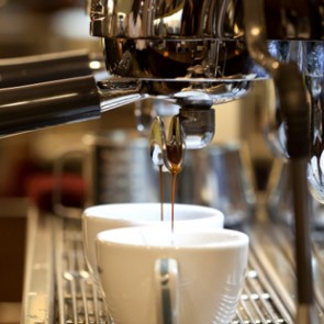 Barista prepares espresso in his coffeeshop; close-up